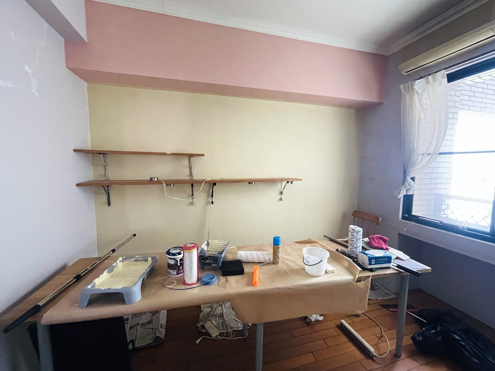 重漆牆面前，桌上擺滿油漆工具